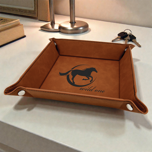 Brown leather tray with horse design and 'wild one' text on a white surface.