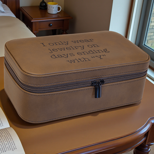 Brown jewelry case with embroidered text on a wooden surface