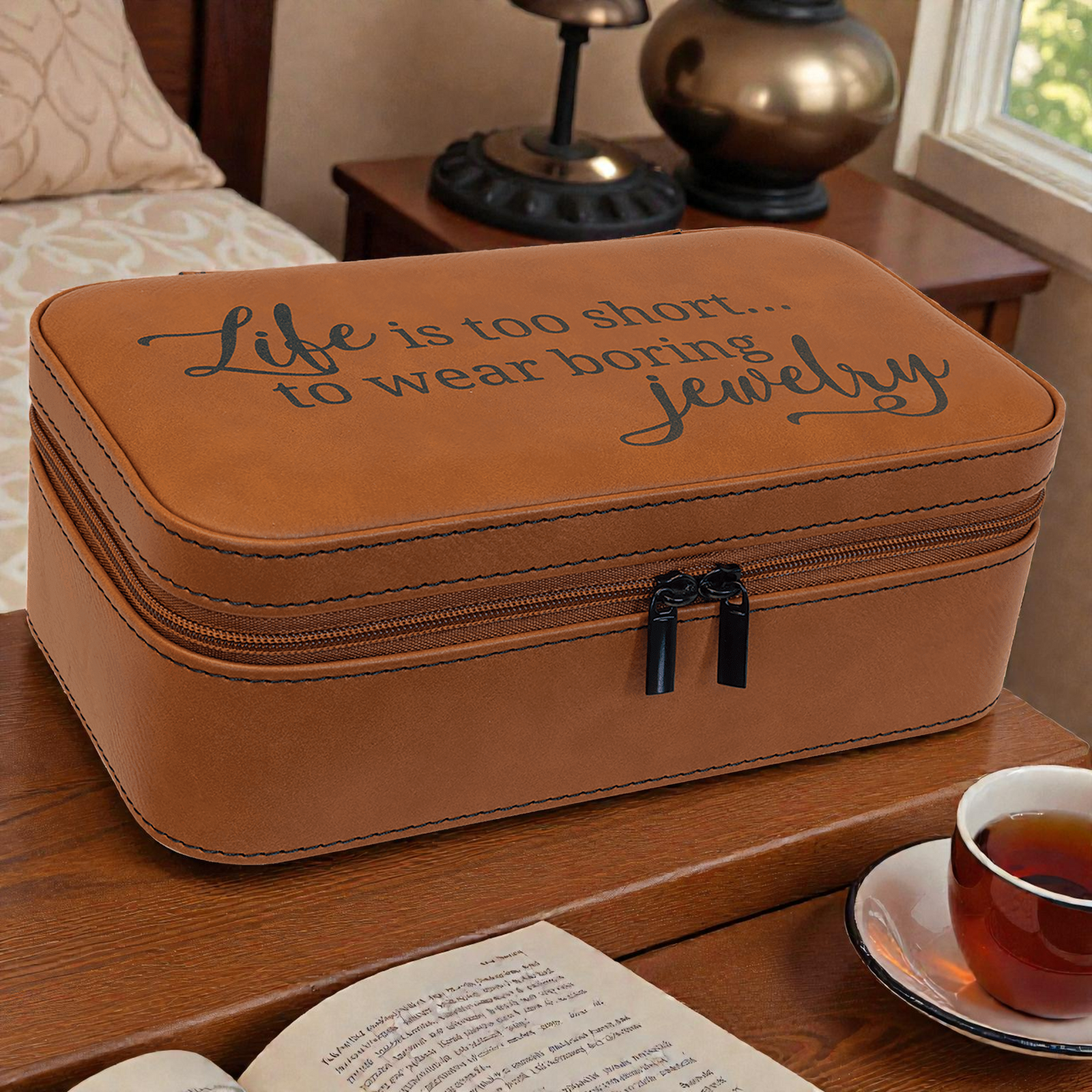 Brown jewelry box with motivational quote on a wooden surface with a cup of tea and book.