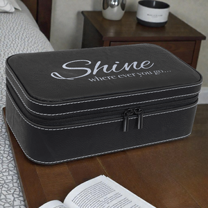 Black travel case with 'Shine wherever you go' text on a wooden surface.