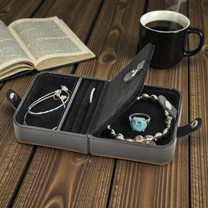 Jewelry set in a black jewelry case on a wooden table with a book and coffee cup in the background.