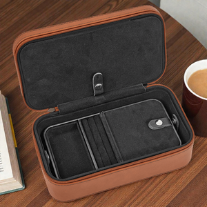 Brown travel case with black interior on a wooden surface next to a book and cup of coffee.