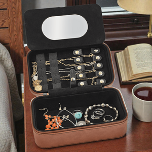 Jewelry case with necklaces, earrings, and rings on a wooden surface.