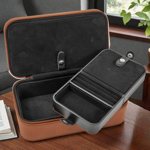 Open brown travel case with black interior on a wooden surface