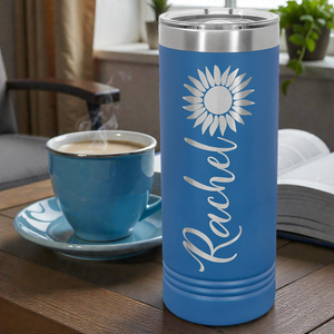 Royal Blue insulated tumbler with a sunflower design and 'Rachel' text, next to a steaming cup of coffee on a wooden table.