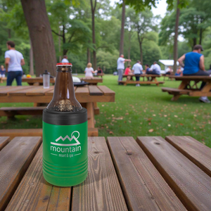 Brown bottle with green sleeve on a wooden table in a park setting